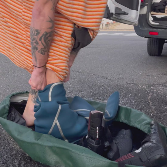 Surfer using the clamshell bag wetsuit changing bag and wetsuit mat